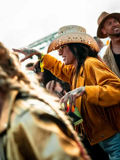 Asistente con sombrero bailando entre el público, de día